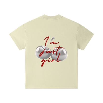 A cream-colored short-sleeve t-shirt with a graphic on the front featuring two metallic silver eggs and the red cursive text 'I'm just girl' with a small bird.