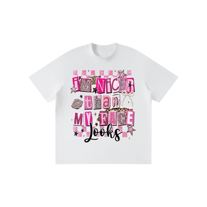 A white short-sleeve crewneck t-shirt featuring a colorful graphic print on the front with the text 'I'm nicer than my race' in pink, leopard print, and black lettering.